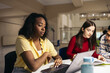 © Pedro Merino/Stocksy - Students doing work and studying with laptops and notes in the college