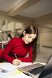 © Pedro Merino/Stocksy - Student in the library studying and working with laptop