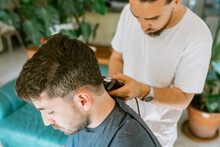 A Man Cutting His Friend's Hair At Home