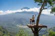 © Julija - Father and daughter tourists enjoying travel around Bali island , Indonesia. They stands on photo location on the tree with view on Agung Mountain