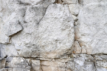 An old white stone wall made of big natural rocks as a background