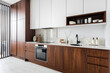 © Luciano Spinelli/Stocksy - Modern kitchen with wood cabinetry covering fridge freezer dishwasher