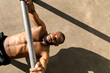 © Artem Podrez/Stocksy - A young man pulls himself up on a horizontal bar on the workout area.