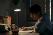 © BONNINSTUDIO/Stocksy - Teenage male studying late night at home