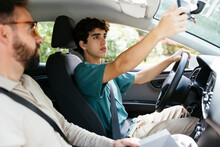 Male driving school instructor teaching to drive a teen boy