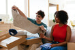 © BONNINSTUDIO/Stocksy - Cheerful diverse friends unpacking boxes in living room