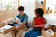 © BONNINSTUDIO/Stocksy - Cheerful diverse friends unpacking boxes in living room