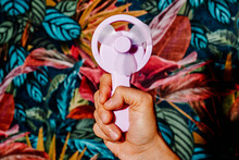 Sweating Man Uses A Pink Manually Operated Fan