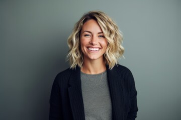 Lifestyle portrait photography of a grinning woman in her 30s wearing a chic cardigan against a minimalist or empty room background