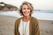 Medium shot portrait photography of a pleased woman in her 50s wearing a chic cardigan against a beach background