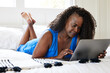 © Trinette Reed/Stocksy - Mature Black woman on computer at home in bed in bedroom