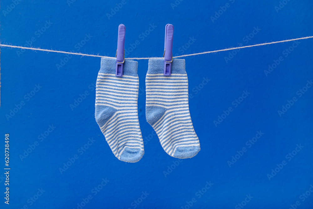 Pair of baby socks hanging on rope against blue background