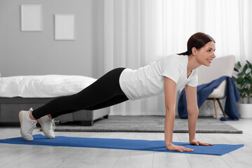 Poster - Happy woman doing plank exercise at home. Morning routine