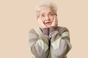 Canvas Print - Shocked senior woman on beige background