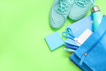 Poster - Sneakers with backpack, bottle of water and different stationery on green background