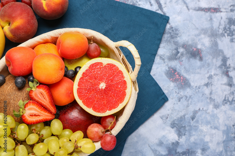 Wicker basket with different fresh fruits on blue background