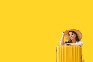 Poster - Young woman with suitcase on yellow background