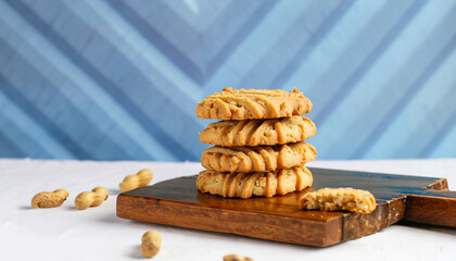 Peanut butter cookies stack on wooden cutting board. Traditional american dessert, nutrition snack, dessert or breakfast food. Blue and white background. Closeup food. Criss cross patterned biscuits.