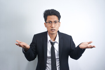 I don't know, who cares. Portrait of confused Asian man with in suit shrugging shoulders, making no idea gesture, whatever. indoor studio shot isolated on white background