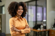 © Wasana - Portrait of confident female professional standing with arms crossed at workplace.