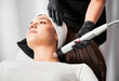 Doctor cosmetologist using radiofrequency microneedling device while performing rejuvenation procedure in cosmetology clinic. Woman receiving skincare treatment in beauty salon.