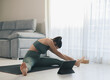 © ADDICTIVE STOCK - Slim anonymous woman stretching legs on mat at home