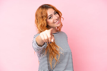 Wall Mural - young caucasian woman isolated on pink background pointing front with happy expression