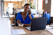 © Wavebreak Media - Portrait of happy african american casual businesswoman talking on smartphone and having lunch