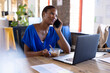 © Wavebreak Media - Happy african american casual businesswoman talking on smartphone and having lunch in office
