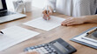 © rogerphoto - Woman accountant using a calculator and laptop computer while counting taxes with colleague at wooden desk in office. Teamwork in business audit and finance