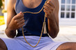 © Wavebreak Media - Midsection of biracial man practicing yoga meditation sitting in sunny garden holding beads