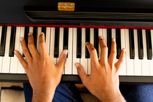 Hands Of Biracial Man Playing Piano At Home In Sunny Room