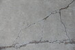 Dry light grey concrete slab with bnumerous cracks