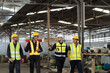 © amorn - Group of male factory workers discussing of their work in industry factory, wearing safety uniform and helmet. Factory workers working in factory