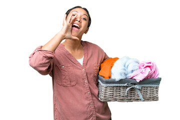 Wall Mural - Young Uruguayan woman holding a clothes basket over isolated chroma key background shouting with mouth wide open