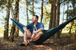 © baranq - Adult man resting sitting in hammock during summer trip in forest