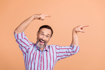 Wall Mural - Photo of astonished cheerful man direct fingers empty space information news isolated on beige color background