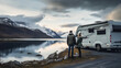 Couple with RV Camper Motor Home looking at lake and mountains during Vacation