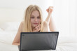© PKpix - Relaxed Woman Working from Bed with Laptop in a Cozy Bedroom.