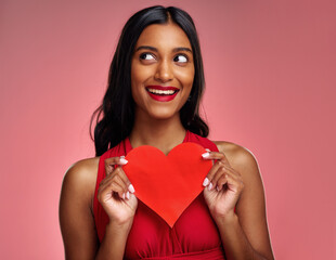 Poster - Thinking, heart and valentines day with a woman on a pink background in studio for love or romance. Idea, red emoji and social media with an excited young female holding a shape or symbol of care