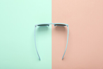 Wall Mural - Top view stylish sunglasses on blue pink pastel background