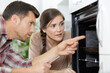 © auremar - woman looking at worker repairing oven