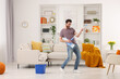 © New Africa - Spring cleaning. Man in headphones with mop singing while tidying up living room