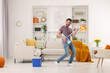© New Africa - Spring cleaning. Man in headphones with mop singing while tidying up living room