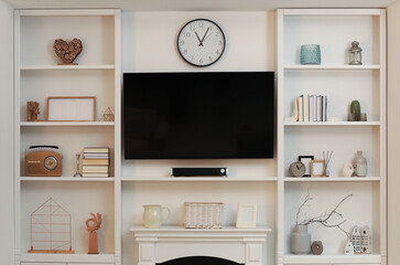 Poster - Stylish shelves with different decor elements and TV set in living room. Interior design