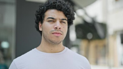 Sticker - Young latin man standing with serious expression at street