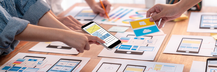 Wall Mural - panorama shot of front-end developer team brainstorming ui and ux designs for mobile app on paper wi
