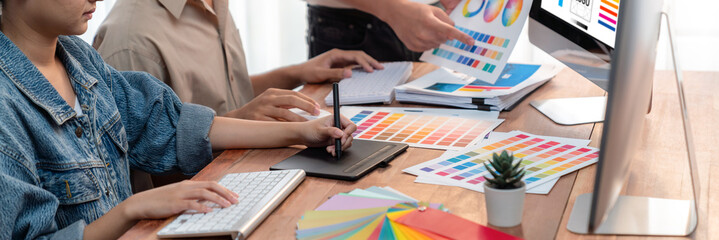 Fototapete - Graphic designer work on computer laptop and with graphic drawing pen while brainstorming unique design with professional graphic team in modern digital studio workplace. Panorama shot. Scrutinize