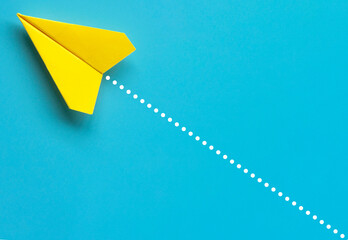 Wall Mural - Top view of yellow paper airplane on blue background. Air transport and copy space