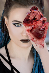Fototapeta girl in black gothic dress with blue hair holding bloody heart